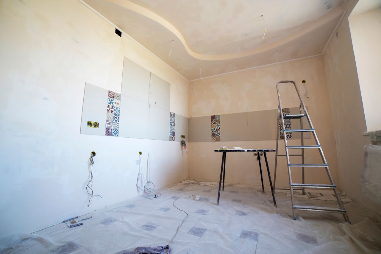 about-us Interior view of a room under renovation with paint, tiles, and tools.