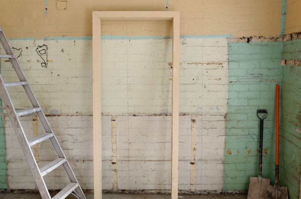 pexels-photo-804394 Renovation scene featuring ladder, frame, and tools against partially demolished walls.